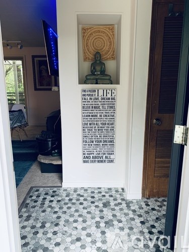 A room with a Buddha statue and a quote on the wall.