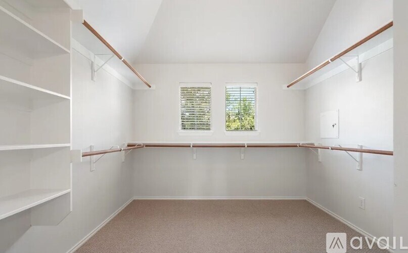 A room with white shelves and a window with blinds.