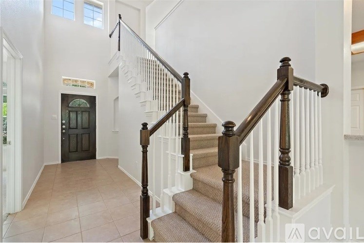 A staircase with a dark wood banister and beige carpeted steps.