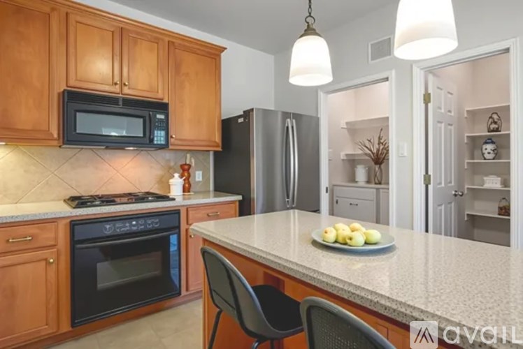 A kitchen with wooden cabinets and a black microwave above the stove.