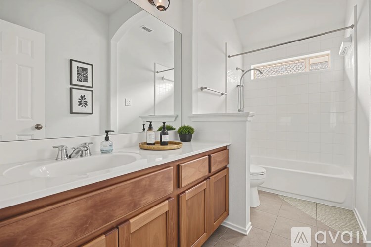 A bathroom with a white sink and a wooden vanity.