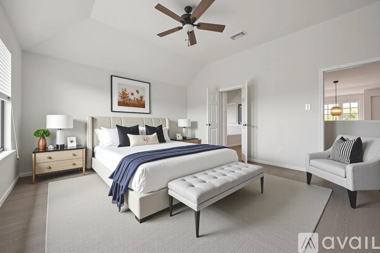 A bedroom with a large bed, a bench, and a ceiling fan.