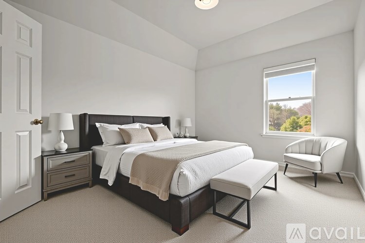 A bedroom with a large bed, a chair, and a window overlooking a landscape.