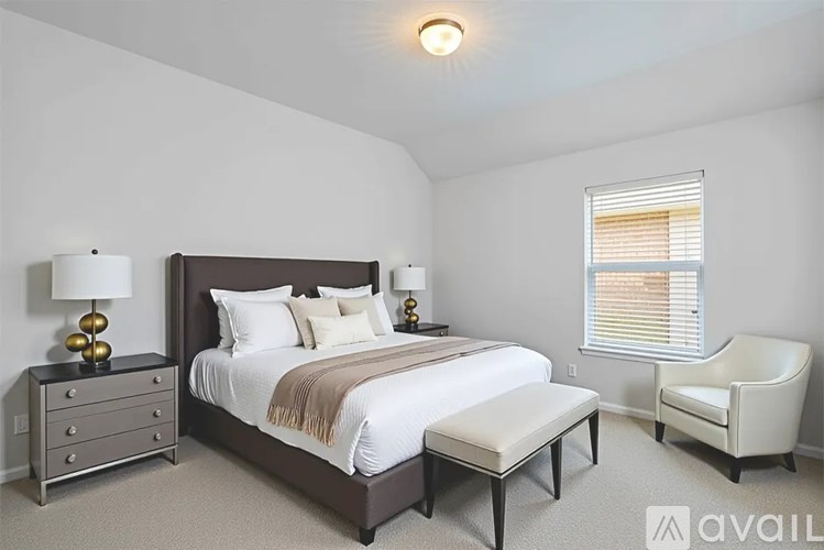 A bedroom with a bed, nightstand, chair, and window.