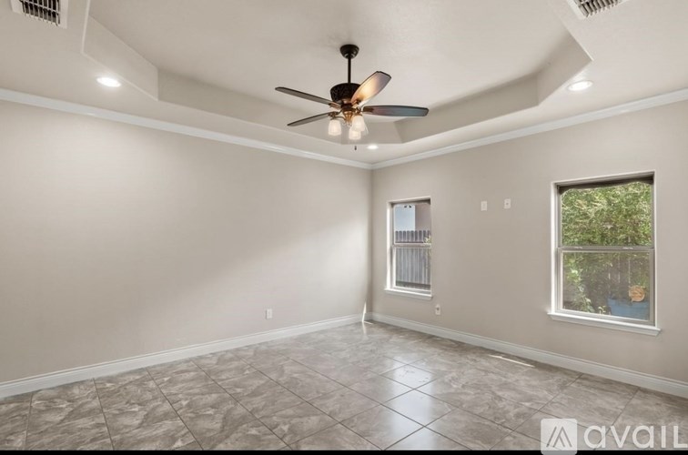 A room with a ceiling fan and a window with a view of trees.