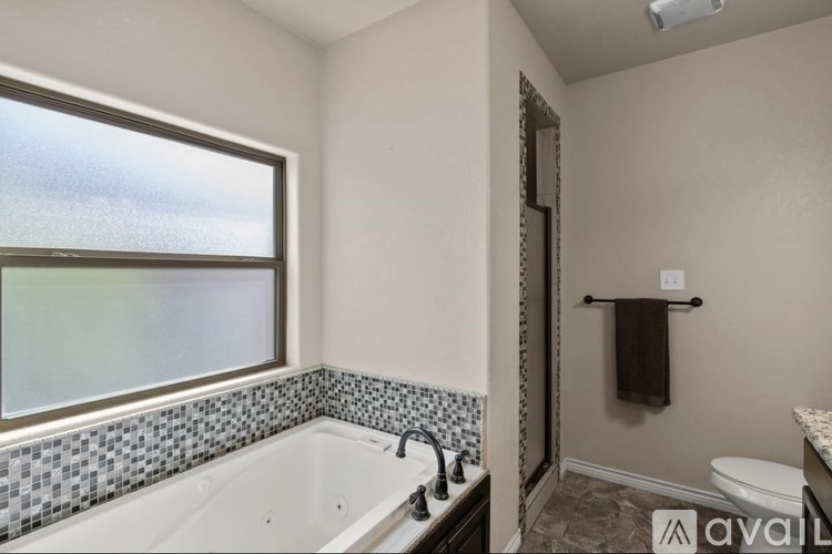 A bathroom with a white tub and a window with a view of the sky.