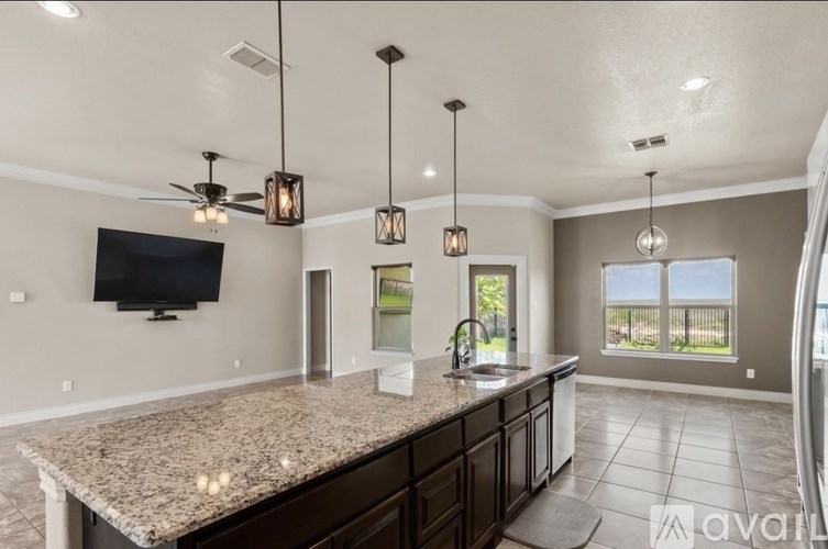 A kitchen with granite countertops and a flat-screen TV mounted on the wall.