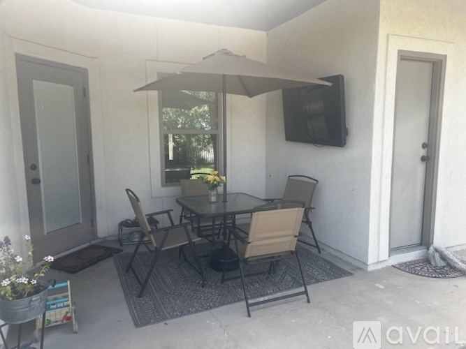 A patio with a table and chairs and a television on the wall.