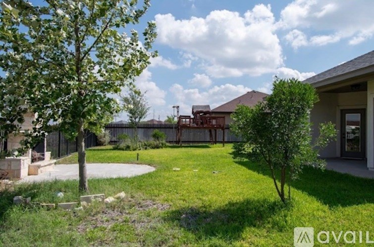 A backyard with a tree, a fence, and a house.