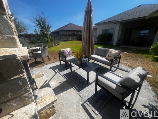 A patio with a table, chairs, and an umbrella.