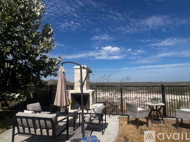 A patio with a table, chairs, and a fireplace overlooks a beach.