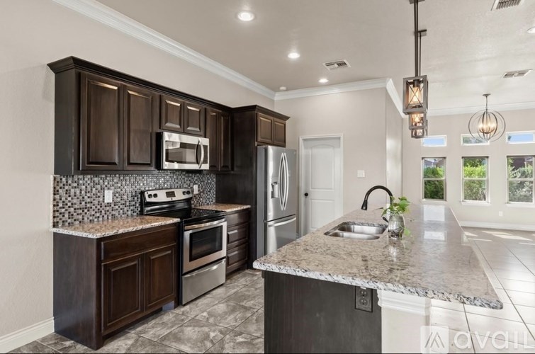 A modern kitchen with dark brown cabinets and a granite countertop.