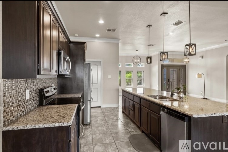 A kitchen with dark wood cabinets and a granite countertop.