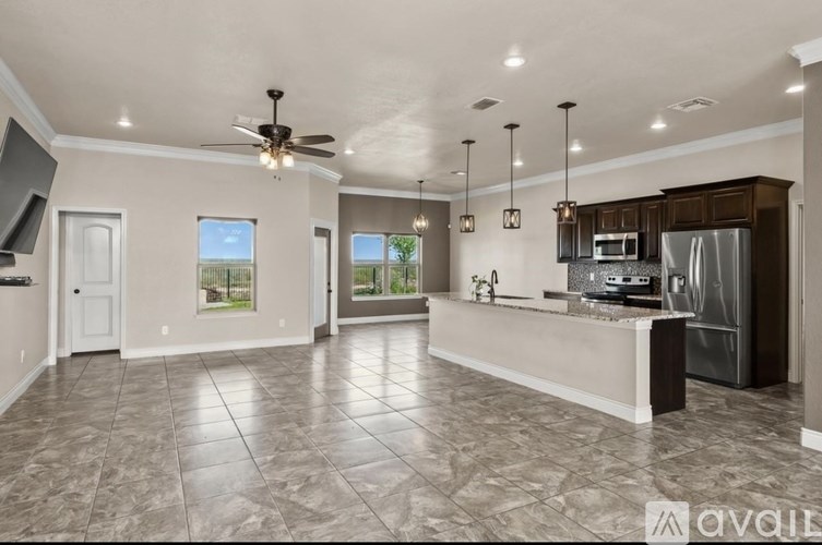 A spacious kitchen and living room with a ceiling fan and tiled flooring.