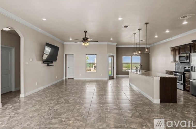 A spacious kitchen and living room with a marble floor and a ceiling fan.