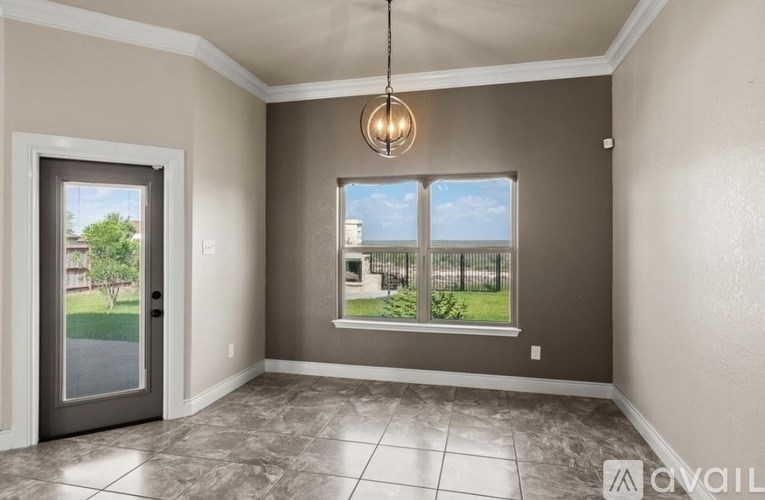 A room with a tiled floor and a large window with a view of a fence and trees.