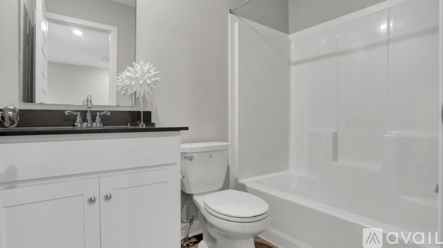 A white toilet sits in a bathroom next to a bathtub.