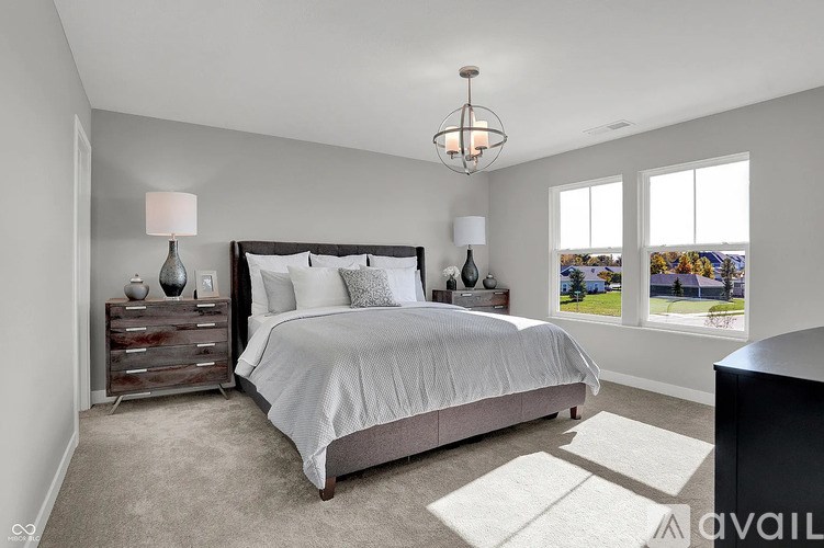 A bedroom with a large bed, a chandelier, and a view of the outdoors through the window.