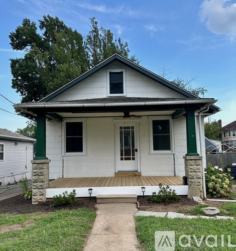 A small white house with a green trim and a porch.