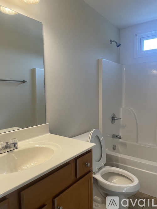 A bathroom with a toilet, sink, and mirror.
