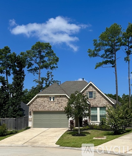 A house with a garage and a driveway is surrounded by trees.