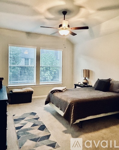 A bedroom with a bed, a bench, and a ceiling fan.