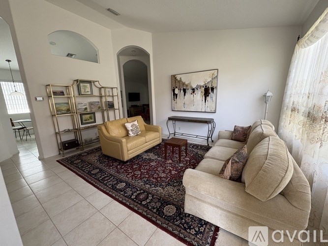A living room with a beige couch and a rug.