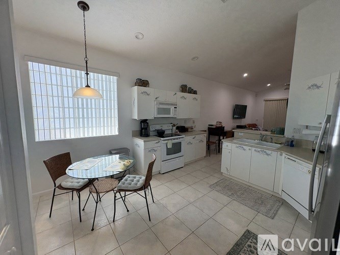 A kitchen with white appliances and a dining table with chairs.