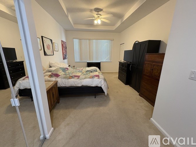 A bedroom with a bed, dresser, and ceiling fan.