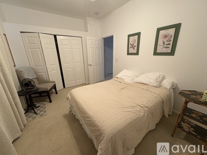 A bedroom with a bed, a chair, and two framed pictures on the wall.