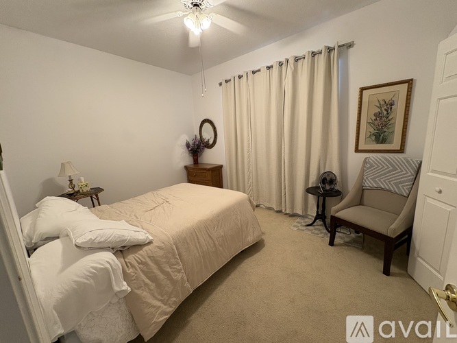 A bedroom with a large bed and a chair.