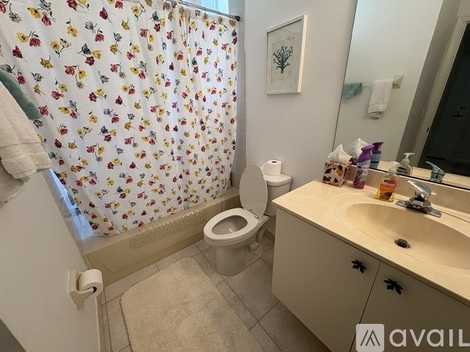 A bathroom with a floral shower curtain and a toilet paper roll on the toilet.