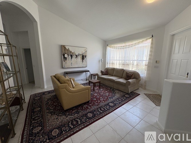 A living room with a rug, a sofa, a chair, and a painting on the wall.