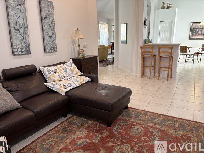 A living room with a brown couch and a rug.