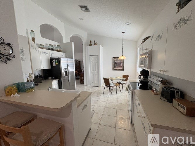 A kitchen with white cabinets and a table with chairs in the middle.