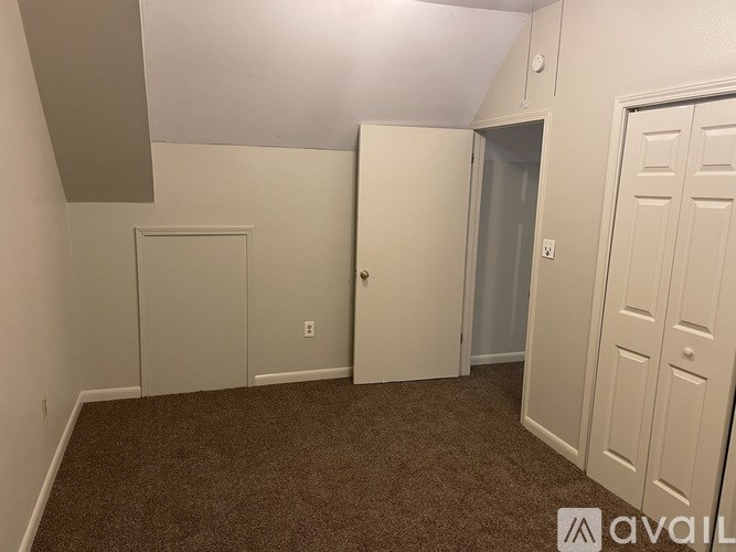A carpeted room with a door on the left and a windowless door on the right.
