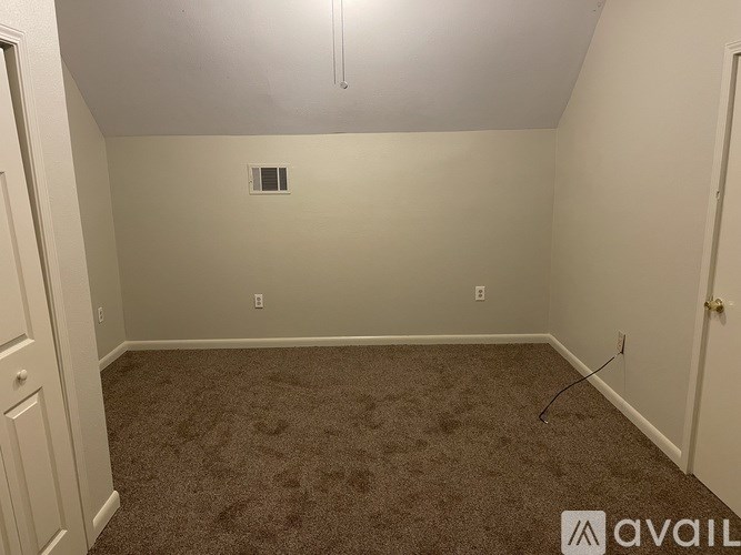 A room with carpeted floor and a small vent on the wall.