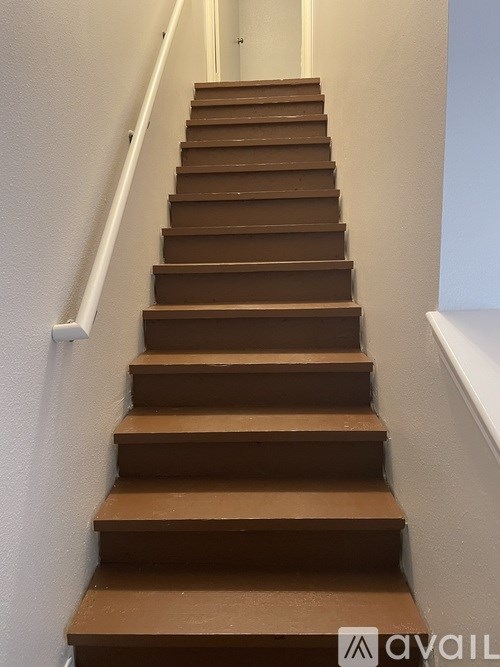 A brown wooden staircase with white handrails.