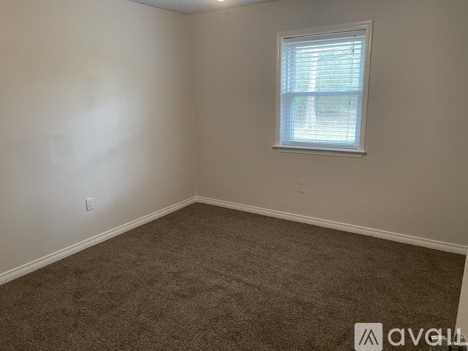 A room with a carpeted floor and a window with blinds.