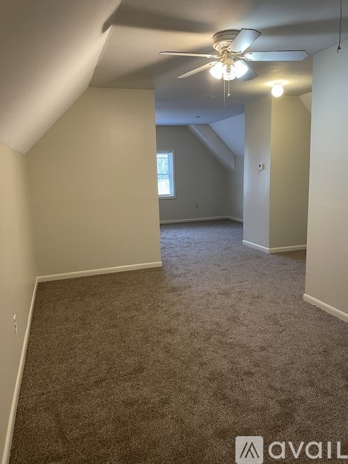 A room with a carpeted floor and a ceiling fan.