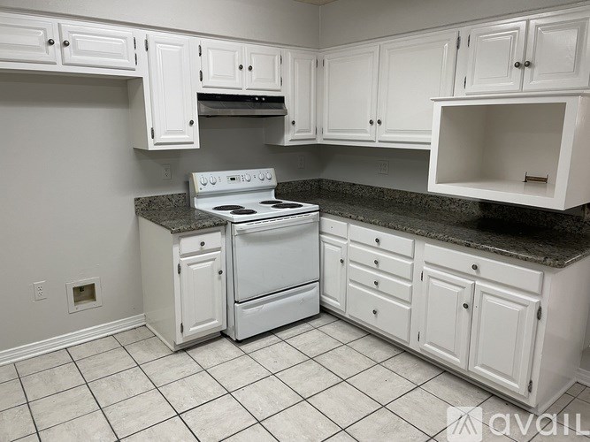 A kitchen with white cabinets and a granite countertop.