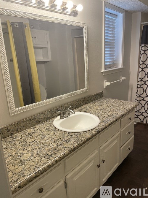A bathroom with a granite countertop and a large mirror.