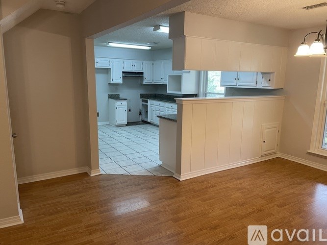 A kitchen with white cabinets and a wooden floor.