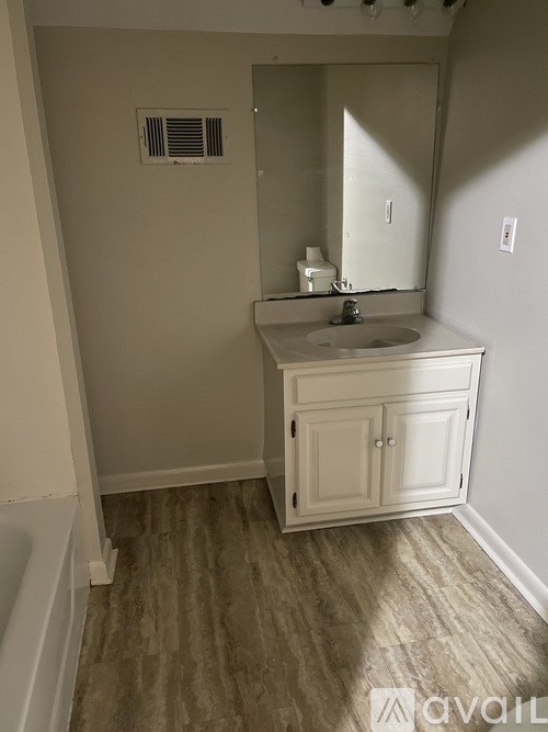 A bathroom with a sink, mirror, and cabinets.