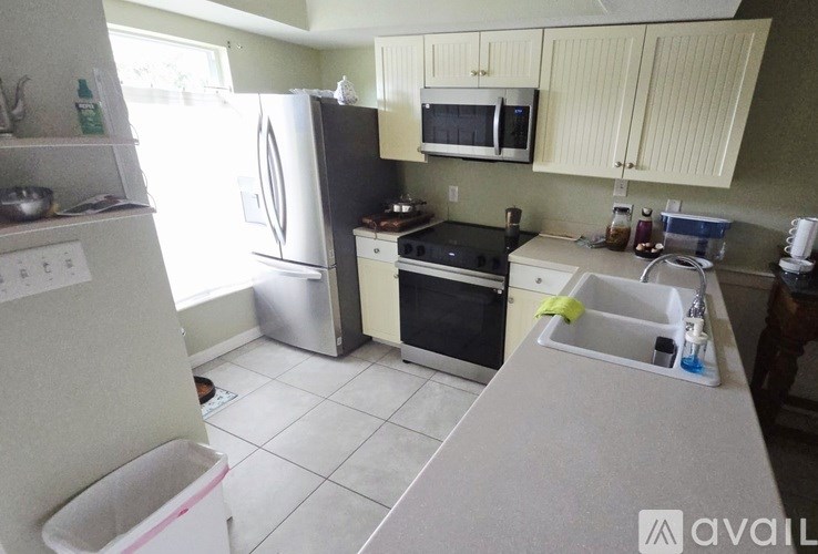 A kitchen with a refrigerator, microwave, oven, and sink.