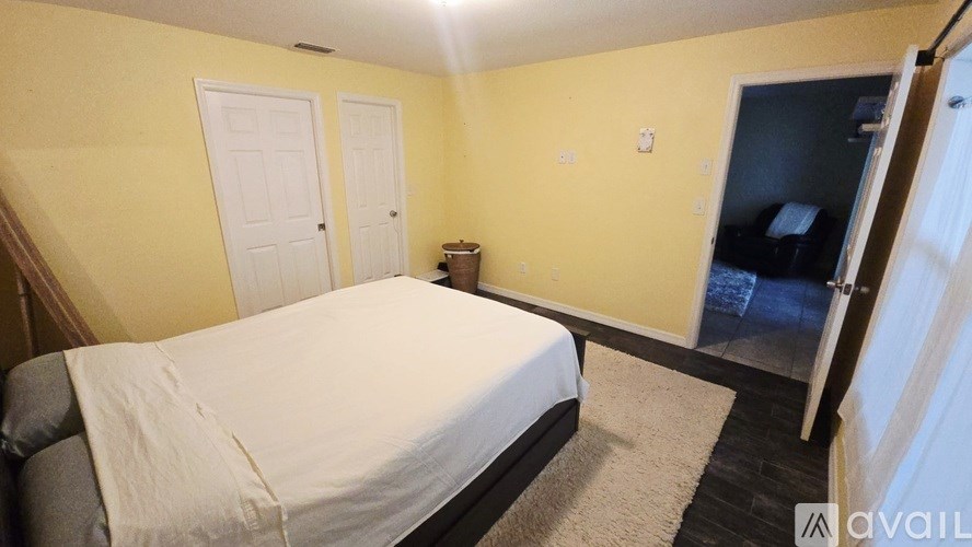 A bedroom with a bed, two doors, and a small table.