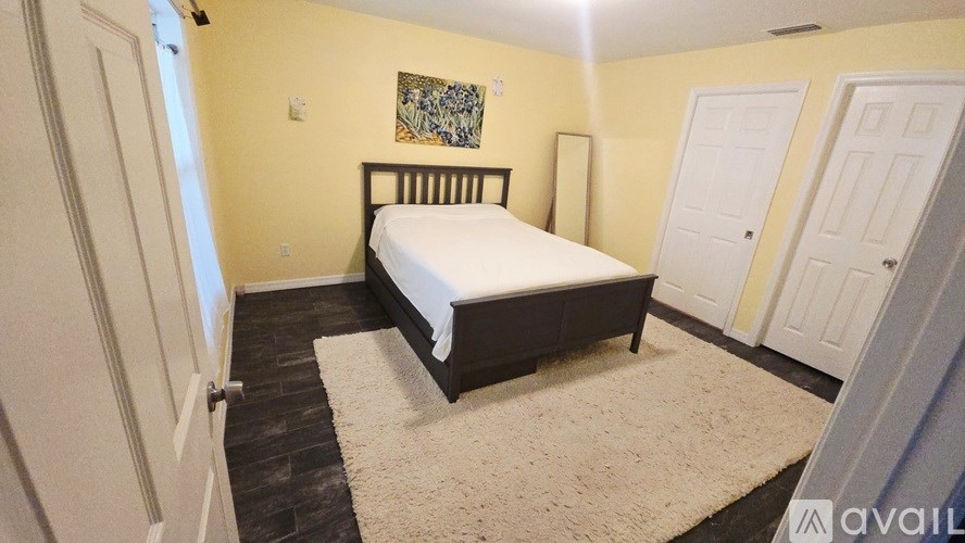 A bedroom with a bed, carpet, and two doors.