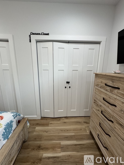 A bedroom with a bed, a dresser, and a wardrobe labeled "Owners Closet".