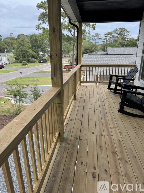 A wooden deck with a bench and a view of a street and trees.