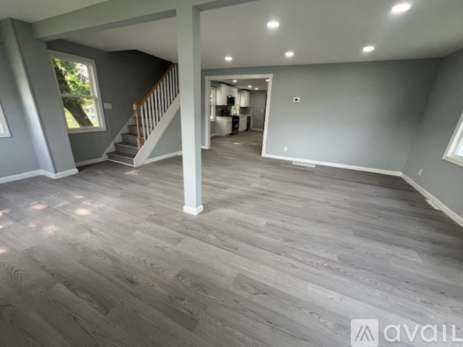 A spacious room with wooden flooring and a staircase leading to another level.